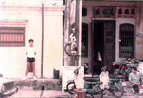   Saw (left) next to his ancestral house in Georgetown. On the right is his brother. 