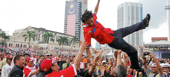 A man is thrown into the air by a crowd during Merdeka Day celebrations in Merdeka Square, Kuala Lumpur, 2008 (source: Wiki Commons)